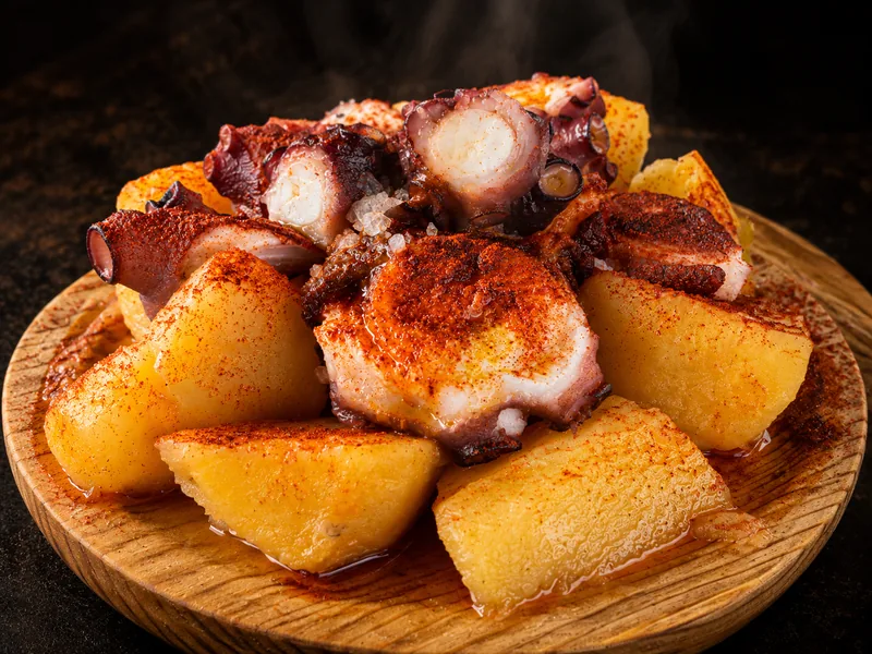 Cachelos con pulpo á feira, pimentón y sal gorda en plato de madera