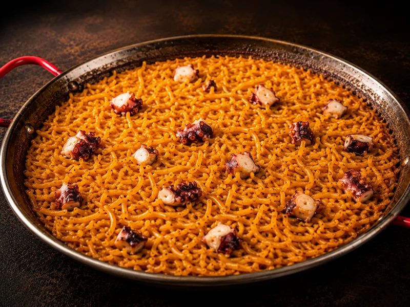 Fideuá dorada con pulpo en paellera de cobre